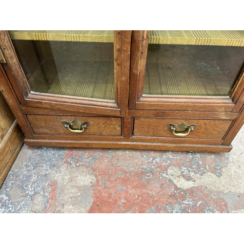 23 - A Georgian oak glazed two door bookcase with two lower drawers - approx. 120cm high x 63cm wide x 27... 