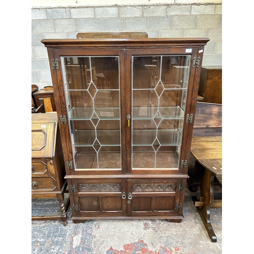 28 - An Old Charm carved oak and lead glazed four door bookcase with two internal glass shelves - approx.... 