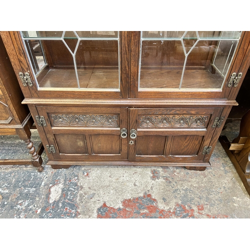 28 - An Old Charm carved oak and lead glazed four door bookcase with two internal glass shelves - approx.... 