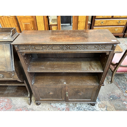 33 - A carved oak two tier bookcase - approx. 107cm high x 91 cm wide x 30cm deep