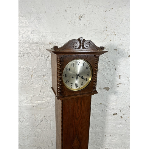 38A - A 1930s oak cased granddaughter clock with key and pendulum - approx. 136cm high