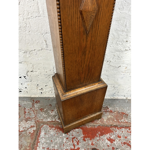 38A - A 1930s oak cased granddaughter clock with key and pendulum - approx. 136cm high