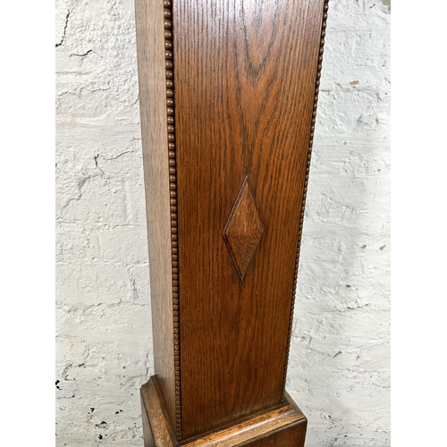 38A - A 1930s oak cased granddaughter clock with key and pendulum - approx. 136cm high