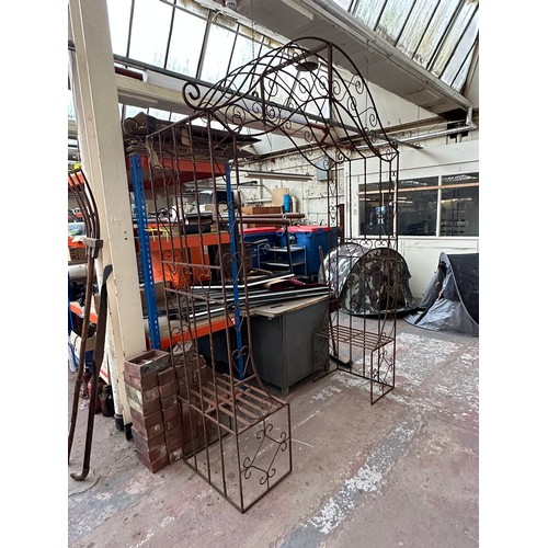 816 - A large wrought iron garden arch with opposing benches - approx. 257cm high x 205cm wide x 61cm deep