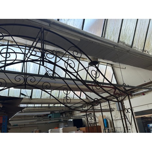 816 - A large wrought iron garden arch with opposing benches - approx. 257cm high x 205cm wide x 61cm deep