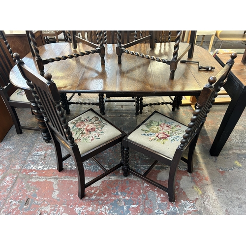 141 - An early 20th century oak wind out dining table and eight chairs with barley twist supports - approx... 