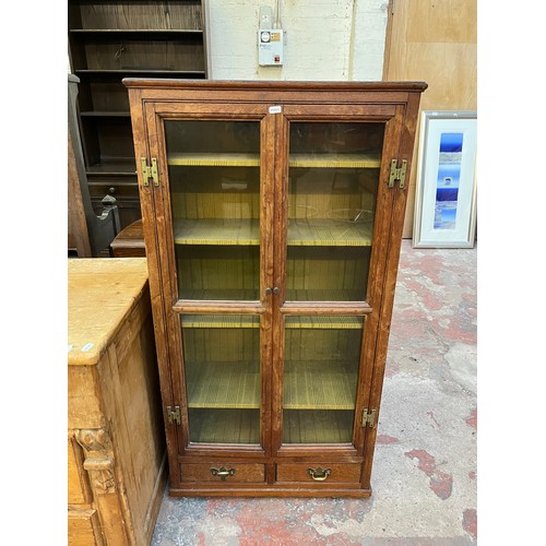 23 - A Georgian oak glazed two door bookcase with two lower drawers - approx. 120cm high x 63cm wide x 27... 