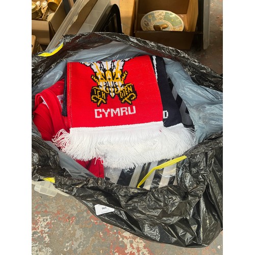 965 - Three bags containing a large quantity of sports scarves and t-shirts to include Liverpool, Wales vs... 