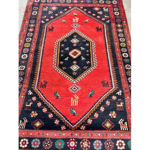 153 - A mid/late 20th century machine woven red rug - approx. 197cm long x 130cm wide
