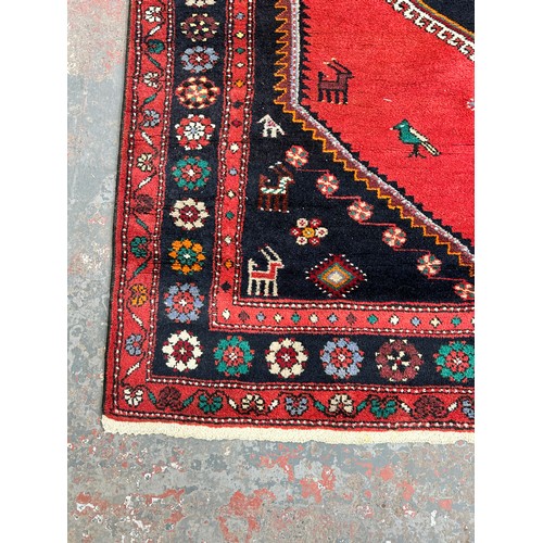 153 - A mid/late 20th century machine woven red rug - approx. 197cm long x 130cm wide