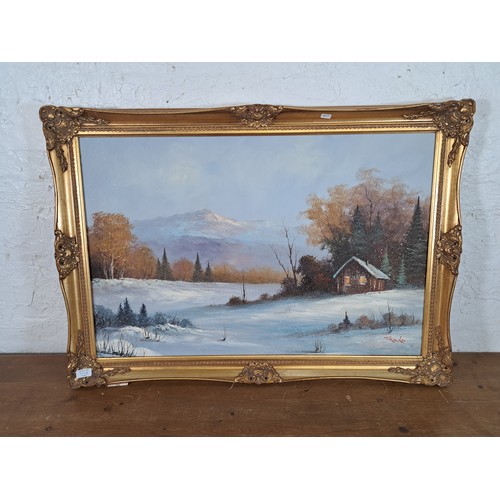 219 - A gilt framed oil on canvas of a winter landscape scene signed lower right - approx. 73cm high x 105... 