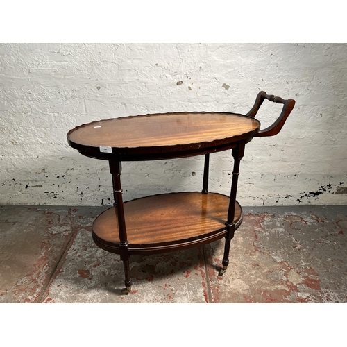 130 - A 19th century style inlaid mahogany pie crust edge oval two tier tea trolley on brass castors - app... 