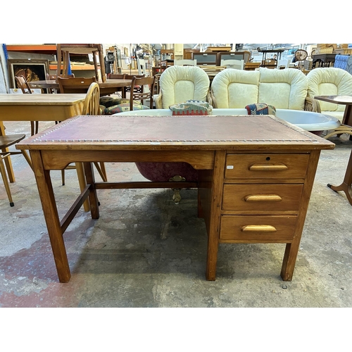 15 - A 1950s stained oak and red leather office desk - approx. 70cm high x 122cm wide x 68cm deep