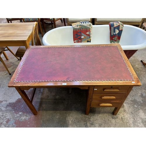 15 - A 1950s stained oak and red leather office desk - approx. 70cm high x 122cm wide x 68cm deep