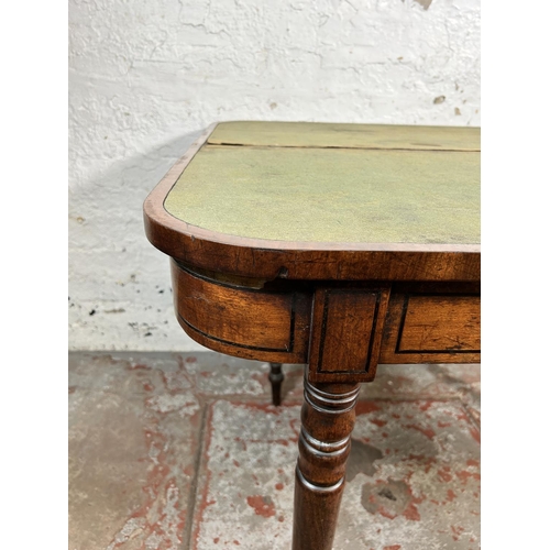 34 - A 19th century ebony inlaid mahogany fold over games table with green baize interior - approx. 74cm ... 