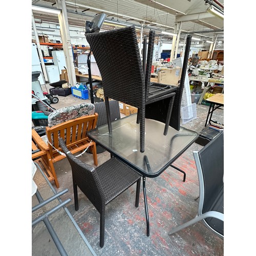 845 - A five piece garden patio set comprising four rattan effect chairs and tubular metal and glass toppe... 