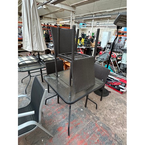 845 - A five piece garden patio set comprising four rattan effect chairs and tubular metal and glass toppe... 