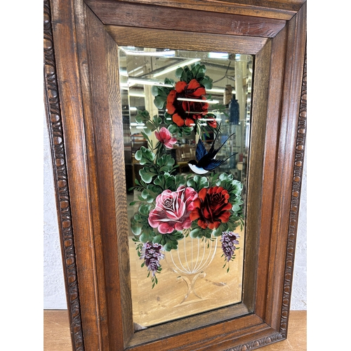 281 - An early 20th century carved oak framed bevelled edge reverse glass painted wall mirror with floral ... 