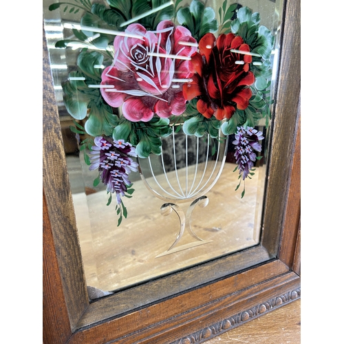 281 - An early 20th century carved oak framed bevelled edge reverse glass painted wall mirror with floral ... 