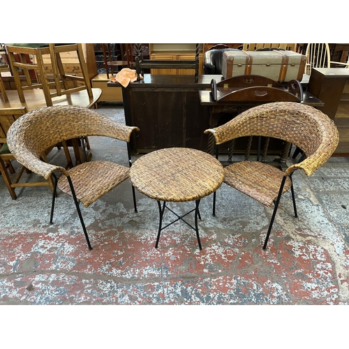 72 - A wicker and black tubular metal three piece patio set comprising two chairs and circular folding ta... 