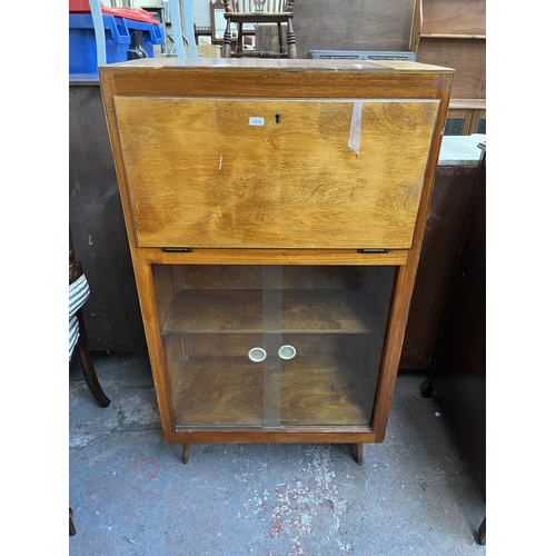 93 - A mid 20th century plywood bureau bookcase with glass sliding doors