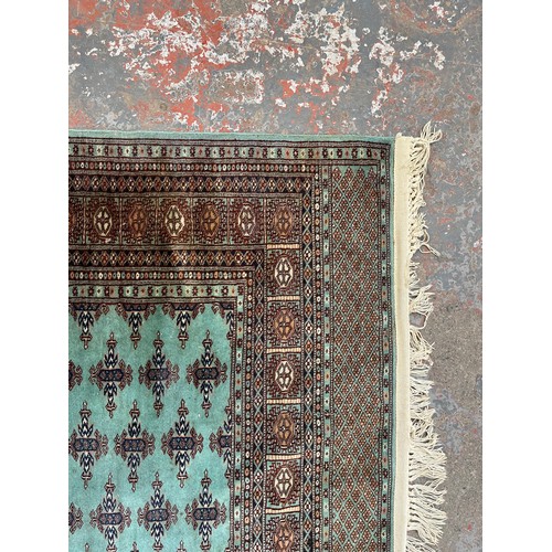 211 - A late 20th century Bokhara turquoise machine woven rug - approx. 193cm x 129cm