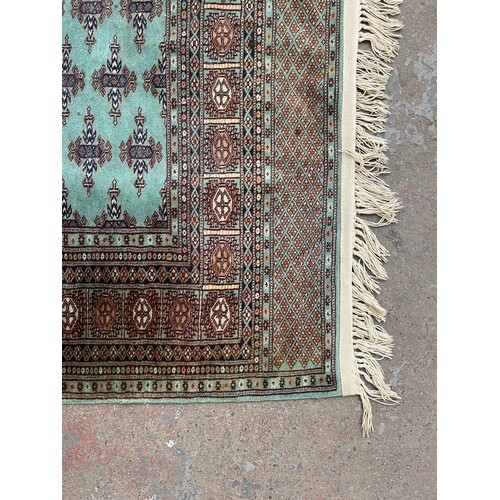 211 - A late 20th century Bokhara turquoise machine woven rug - approx. 193cm x 129cm