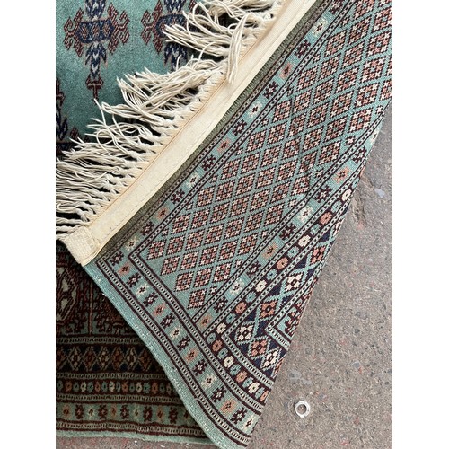 211 - A late 20th century Bokhara turquoise machine woven rug - approx. 193cm x 129cm