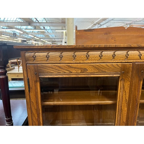 51 - An Ercol Golden Dawn elm bookcase with two glazed doors and two internal shelves - approx. 138cm hig... 