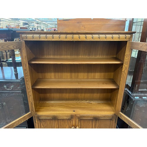 51 - An Ercol Golden Dawn elm bookcase with two glazed doors and two internal shelves - approx. 138cm hig... 