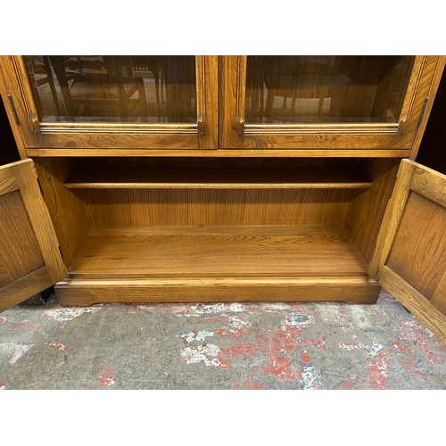 51 - An Ercol Golden Dawn elm bookcase with two glazed doors and two internal shelves - approx. 138cm hig... 