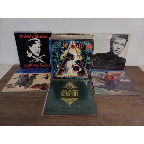 655 - A collection of vinyl records to include Genesis, Eric Clapton, Talking Heads, David Bowie, Peter Ga... 