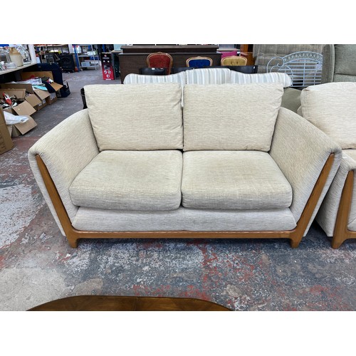 223 - An Ercol beige fabric upholstered and blonde elm three piece lounge suite comprising two seater sofa... 