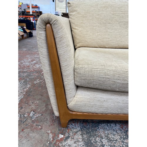 223 - An Ercol beige fabric upholstered and blonde elm three piece lounge suite comprising two seater sofa... 