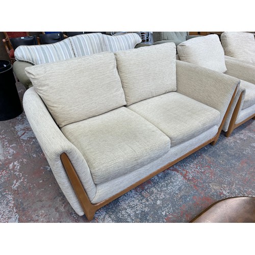 223 - An Ercol beige fabric upholstered and blonde elm three piece lounge suite comprising two seater sofa... 