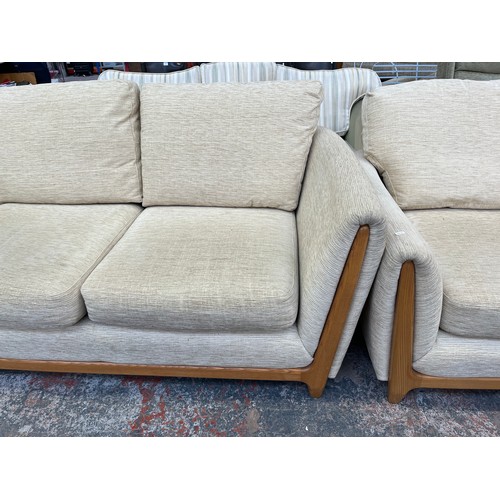 223 - An Ercol beige fabric upholstered and blonde elm three piece lounge suite comprising two seater sofa... 