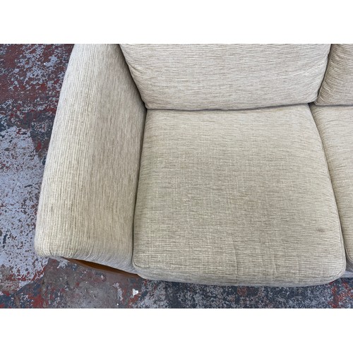 223 - An Ercol beige fabric upholstered and blonde elm three piece lounge suite comprising two seater sofa... 