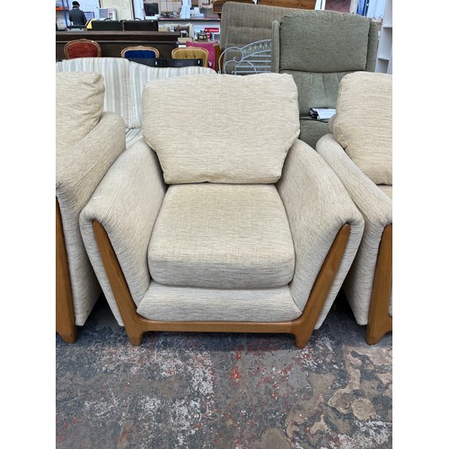 223 - An Ercol beige fabric upholstered and blonde elm three piece lounge suite comprising two seater sofa... 