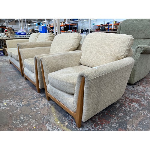 223 - An Ercol beige fabric upholstered and blonde elm three piece lounge suite comprising two seater sofa... 