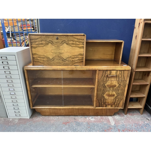 180 - A mid 20th century Art Deco style Rurka walnut drinks cabinet with two glass sliding doors and fall ... 