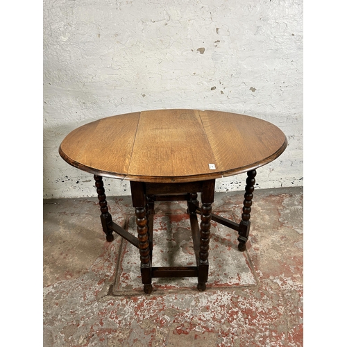 103 - An early 20th century oak drop leaf gate leg oval occasional table on bobbin turned supports - appro... 