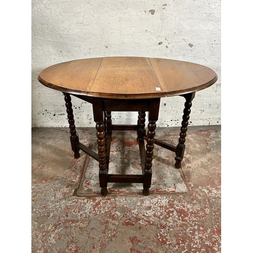 103 - An early 20th century oak drop leaf gate leg oval occasional table on bobbin turned supports - appro... 