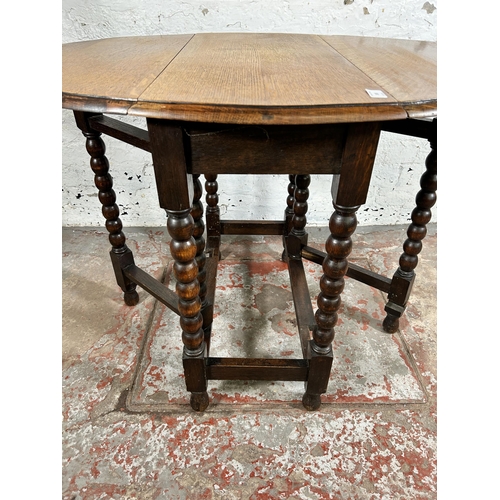 103 - An early 20th century oak drop leaf gate leg oval occasional table on bobbin turned supports - appro... 