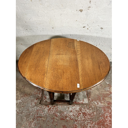 103 - An early 20th century oak drop leaf gate leg oval occasional table on bobbin turned supports - appro... 