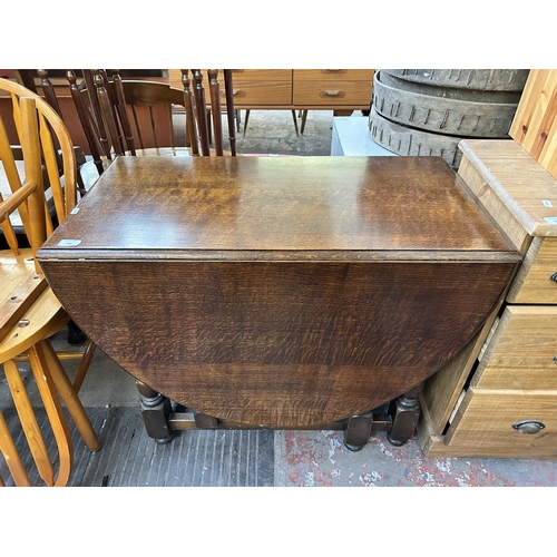 141 - A mid 20th century oak drop leaf gate leg oval dining table