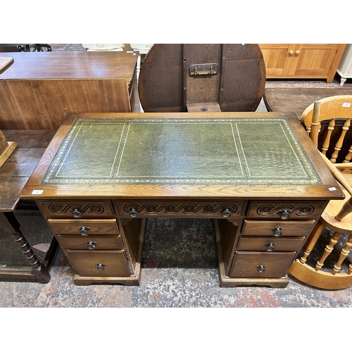 27 - A carved oak and green leather pedestal writing desk - approx. 77cm high x 122cm wide x 61cm deep