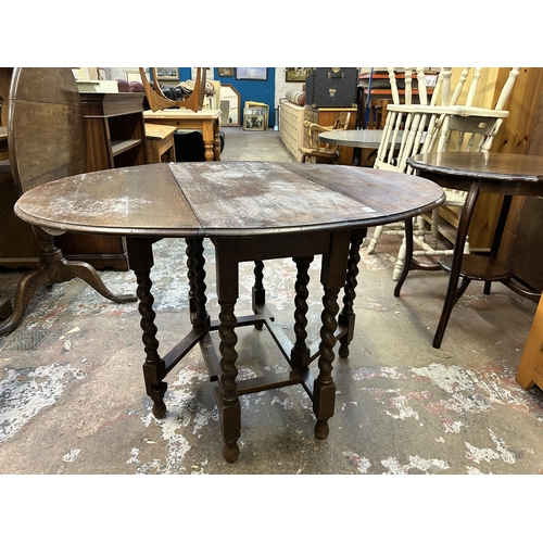 39 - An early 20th century oak drop leaf gate leg oval dining table on barley twist supports - approx. 72... 