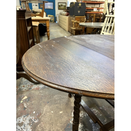 39 - An early 20th century oak drop leaf gate leg oval dining table on barley twist supports - approx. 72... 