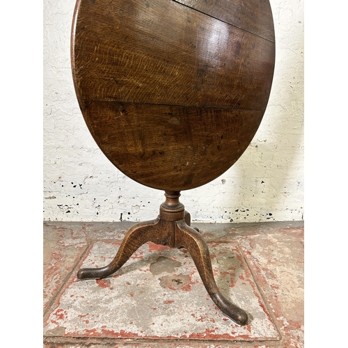 40 - A George III oak circular tilt top tripod occasional table - approx. 114cm high x 78cm in diameter