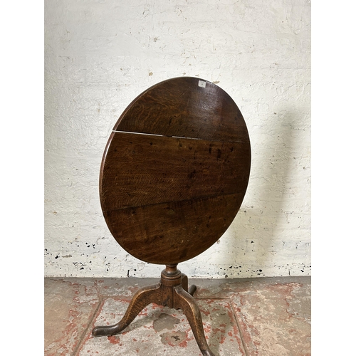 40 - A George III oak circular tilt top tripod occasional table - approx. 114cm high x 78cm in diameter